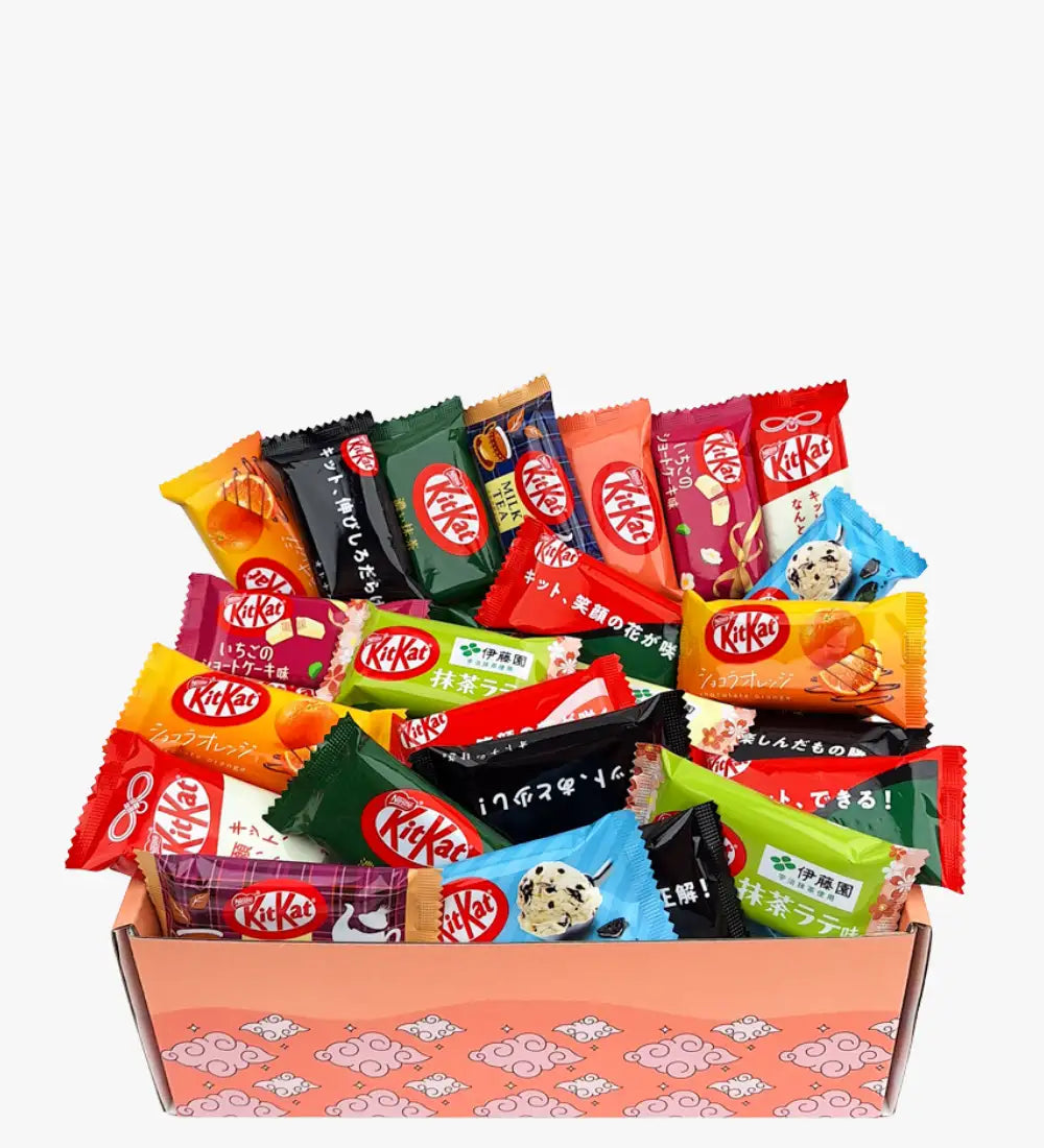 Una vibrante variedad de barras de chocolate KitKat en envoltorios coloridos y variados, anidadas dentro de una caja de regalo con patrón rosa.