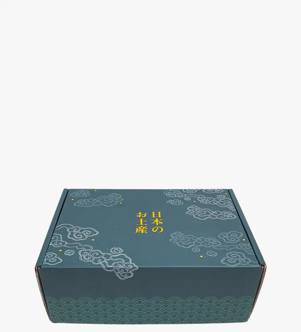Caja de regalo de cartón color turquesa adornada con patrones de nubes y olas blancas, con caracteres japoneses dorados.