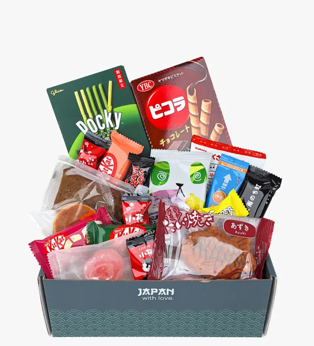 Una caja de regalo gris etiquetada 'Japón con amor' llena de aperitivos japoneses variados, incluyendo Pocky, KitKat y galletas de azuki.