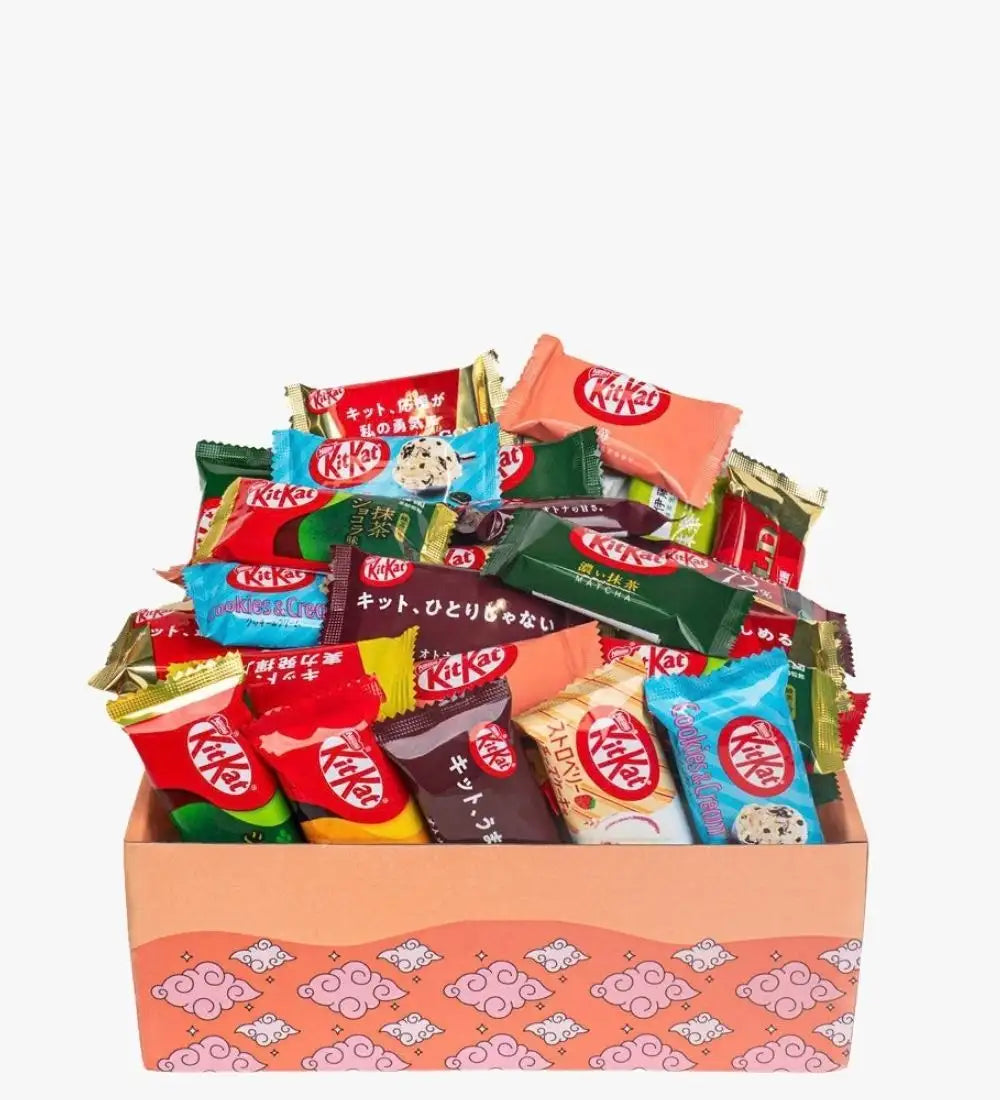 Una variedad vibrante de barras de chocolate Kit Kat en sabores variados y envoltorios coloridos, guardadas dentro de una caja de regalo rosa con estampado.